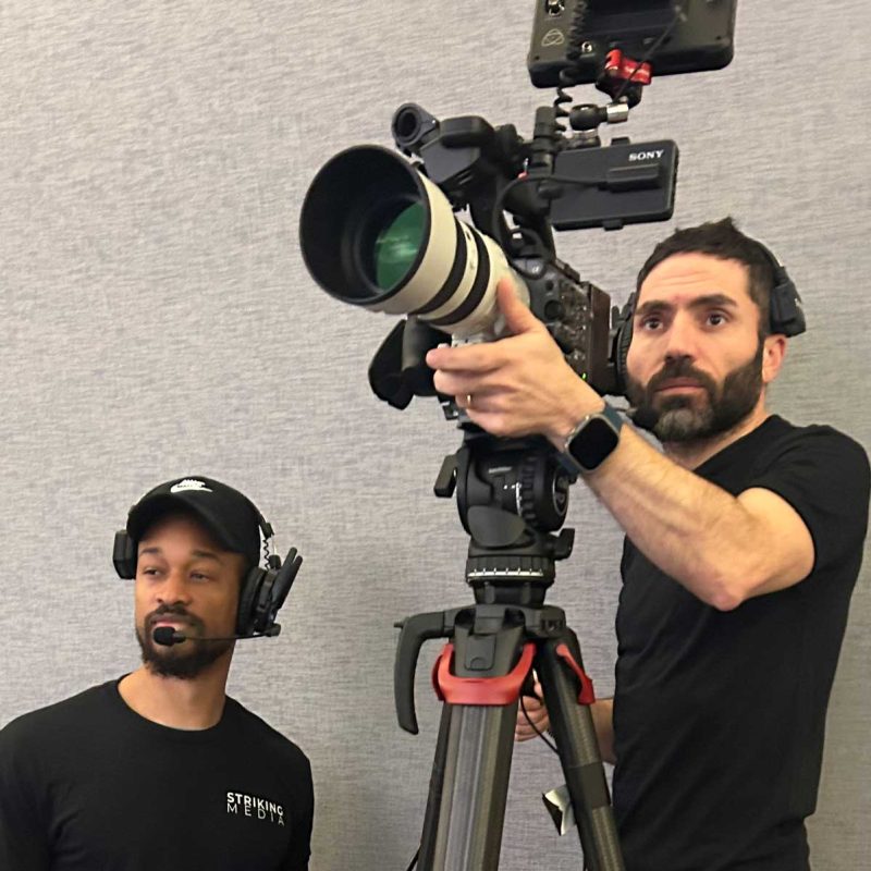 Video cameras filming a speaker and audience at a Washington, DC conference.