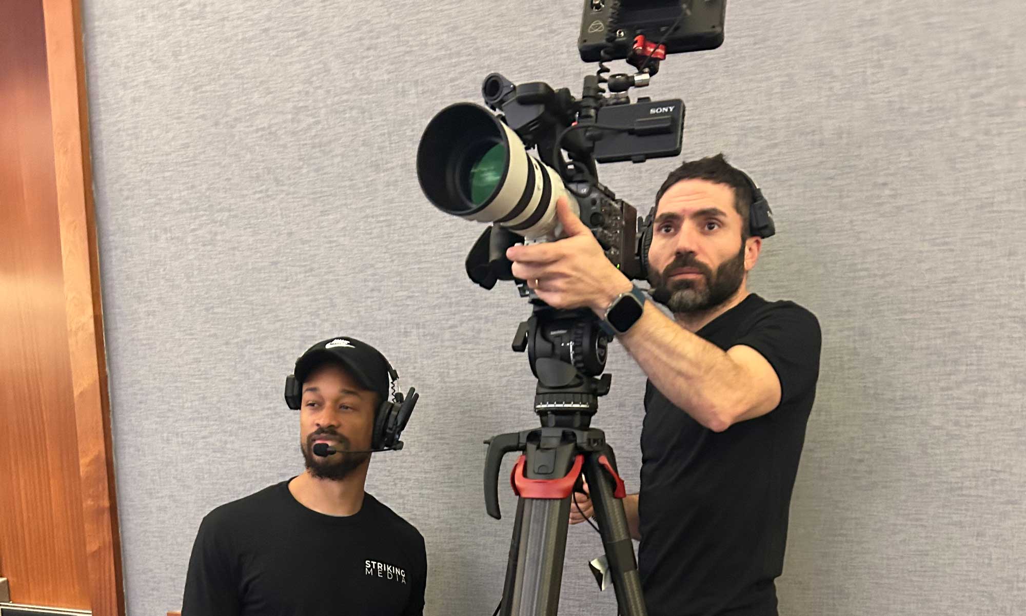Video cameras filming a speaker and audience at a Washington, DC conference.